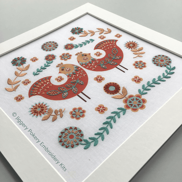 Folk art birds embroidery pattern in mount shown on grey background