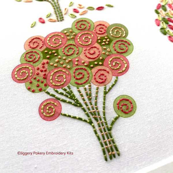 Close-up of simple tree embroidery design in pink, coral and green