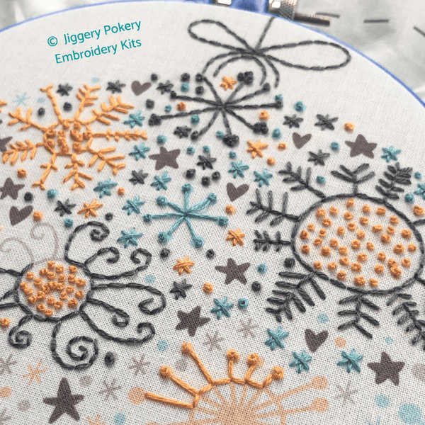 Modern Christmas embroidery in progress showing stitching in grey, teal and orange