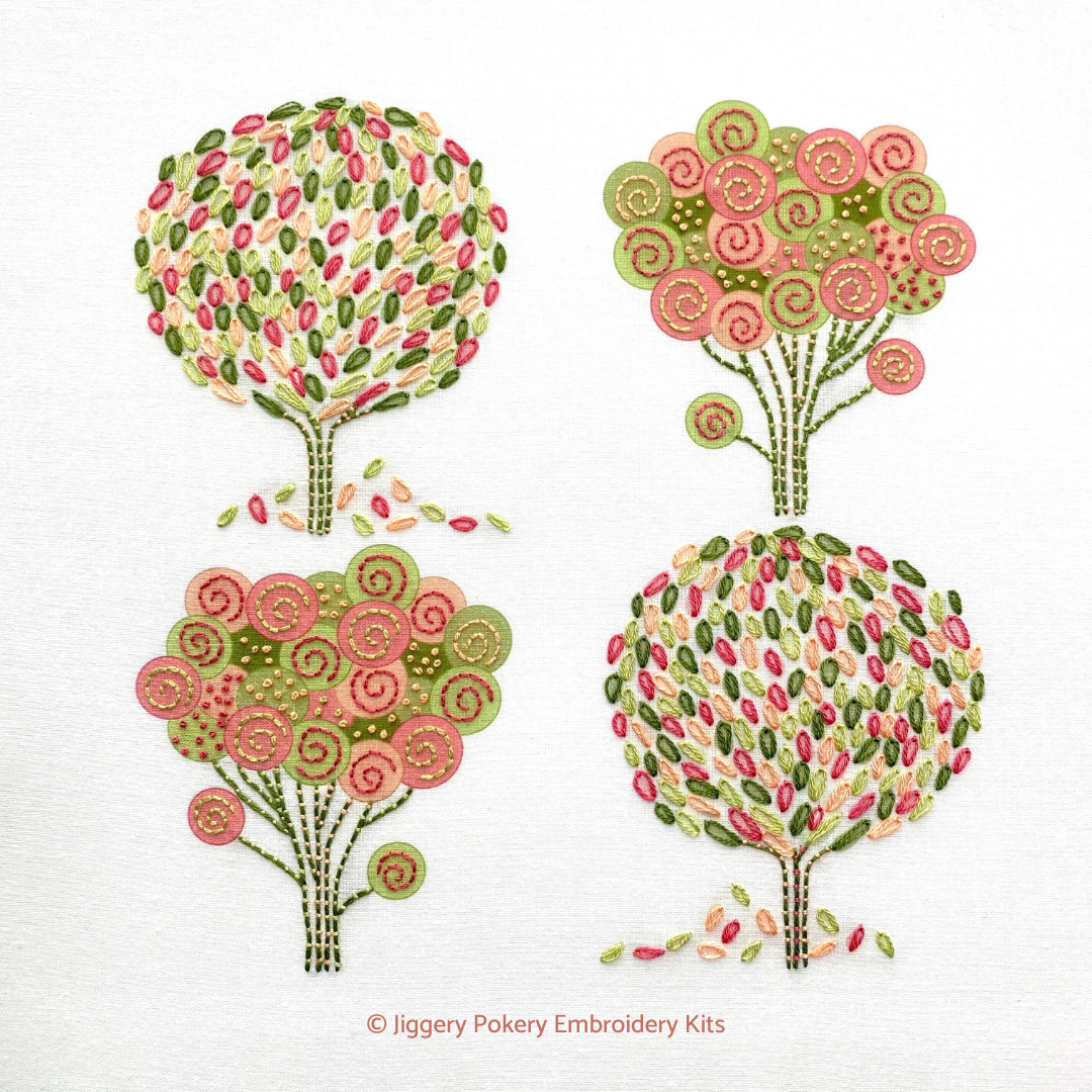 Spring embroidery kit showing four trees stitched in pink, peach and green DMC threads