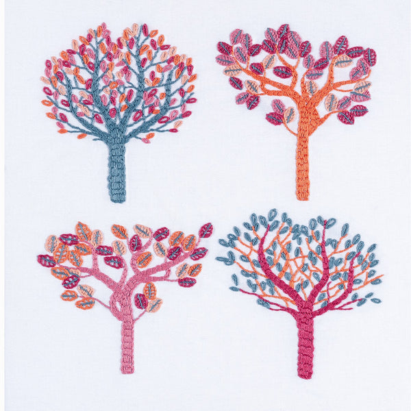 Autumn embroidery showing four trees using non-traditional DMC thread colours of salmon pink, air force blue, crimson, flame and pink.