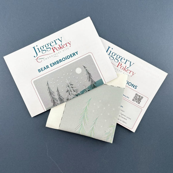 Bear embroidery pattern printed on fabric with instructions, shown on a dark blue background.