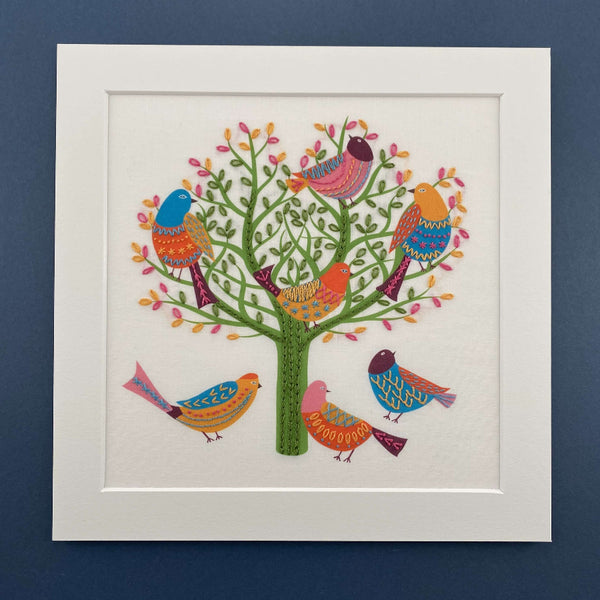 Birds in a tree embroidery pattern mounted on a navy blue background