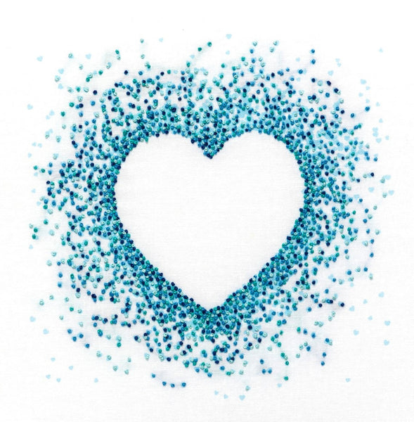 Heart shape made of French knots in 4 shades of blue DMC threads stitched onto a background of tiny blue printed hearts