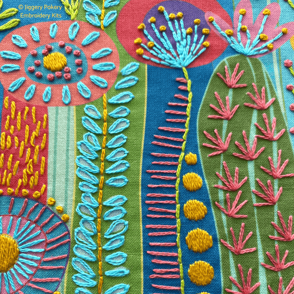 Centre section of cactus embroidery kit showing stitching in bright blue, yellow pink and green close-up