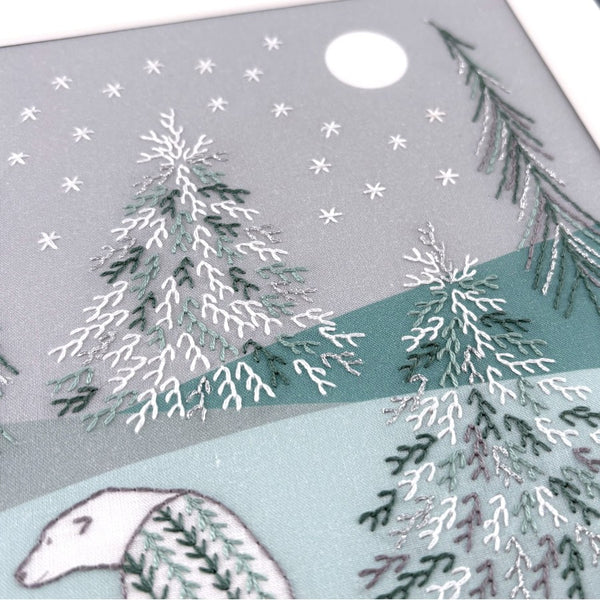 Winter scene with embroidered trees, moon and stars, and a polar bear on a soft green and grey background