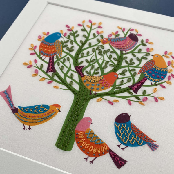 Close-up showing 7 colourful birds in a tree embroidery pattern