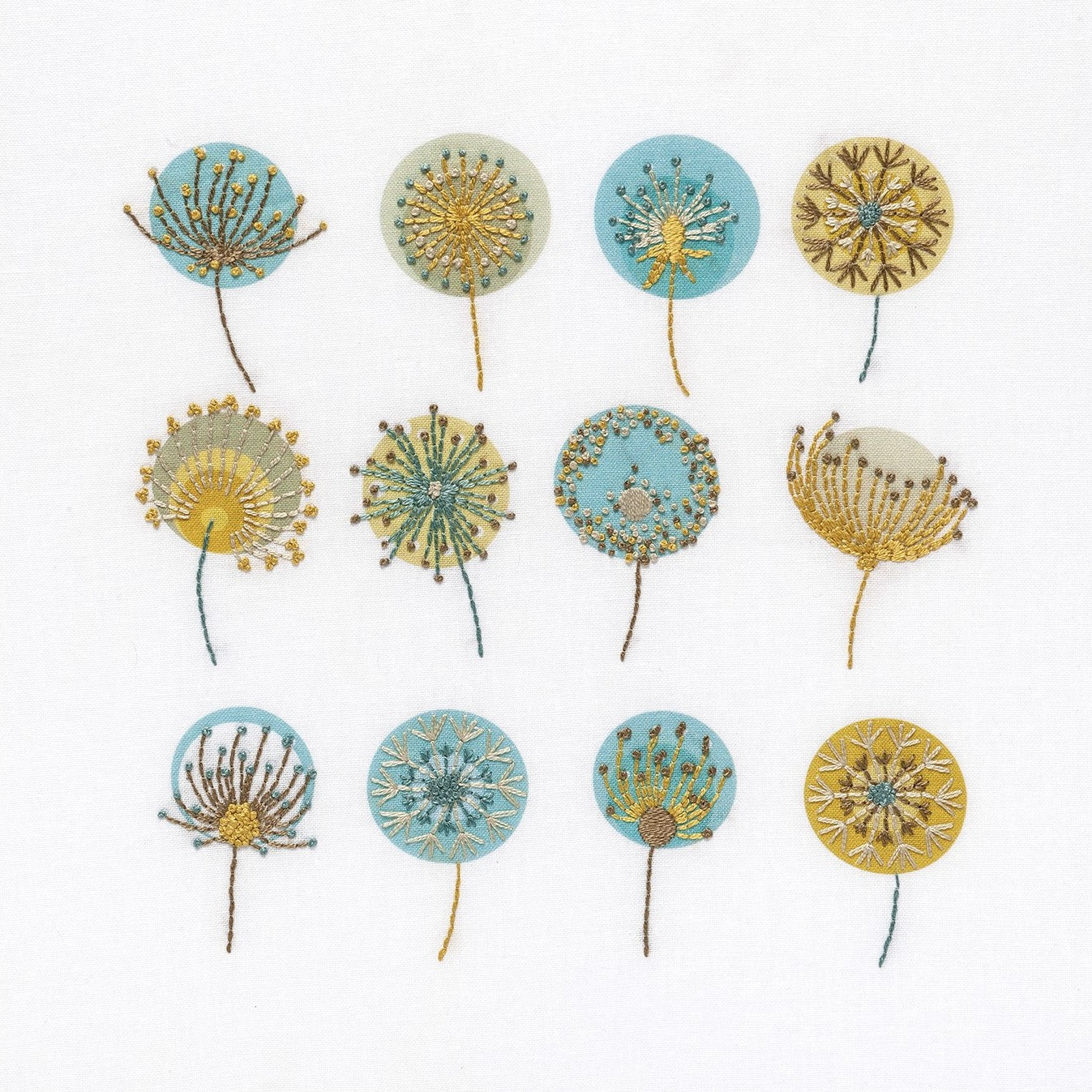 Dandelions embroidery kit shows 12 seed heads stitched in mustard gold, brown, blue and cream DMC thread colours
