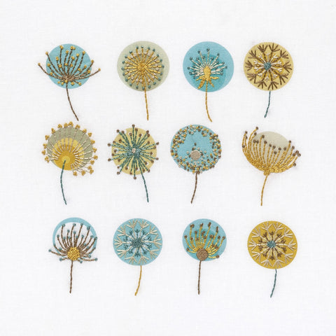 Dandelions embroidery kit shows 12 seed heads stitched in mustard gold, brown, blue and cream DMC thread colours