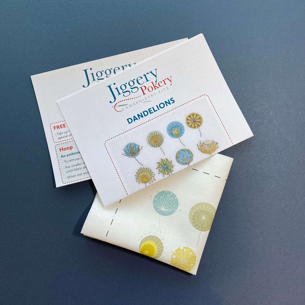 Dandelions embroidery design printed on fabric, shown with stitch instructions and general instructions on dark blue background