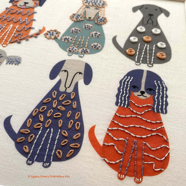 Close-up showing orange dog stitched with couching and a blue dog stitched with lazy daisy stitches