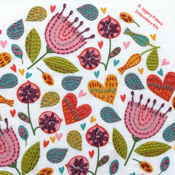 Close-up of embroidery flower pattern showing pink flowers, orange and red hearts and green leaves done in easy embroidery stitches