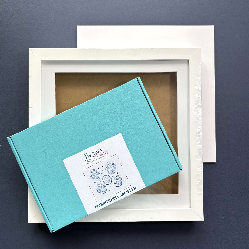 Learn to embroider sampler kit with a square white frame and a piece of mountboard cut to size