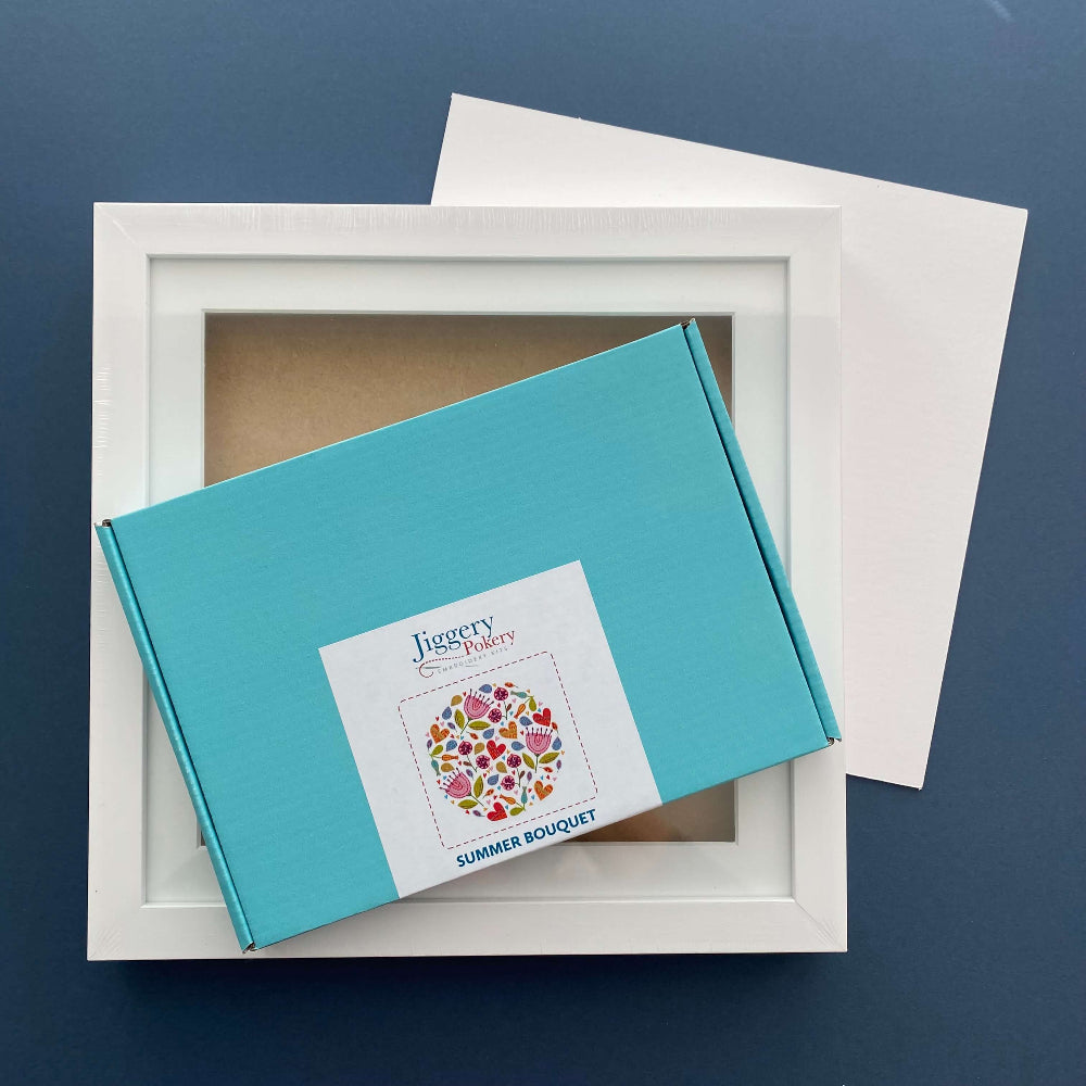 Multicoloured floral embroidery kit with a square white frame and a piece of mountboard cut to size