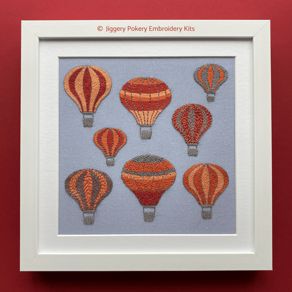 Framed hot air balloon embroidery kit shown on red background
