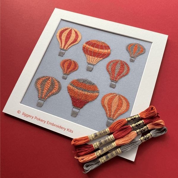 Hot air balloons design shown on red background with DMC threads in orange, red, apricot and grey