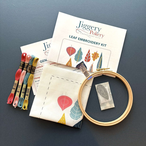Embroidery kit with wooden hoop, 4 skeins of DMC thread, needles and needle threader in a bag, instructions and the leaf pattern printed on fabric.