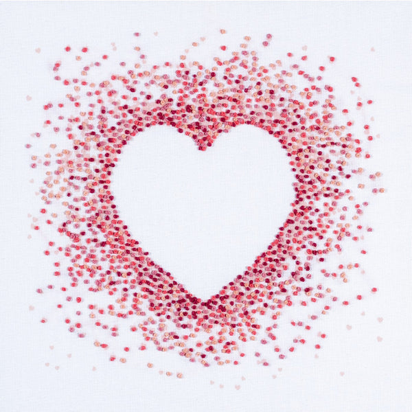 Heart shape made of French knots in 4 shades of blue DMC threads stitched onto a background of tiny blue printed hearts