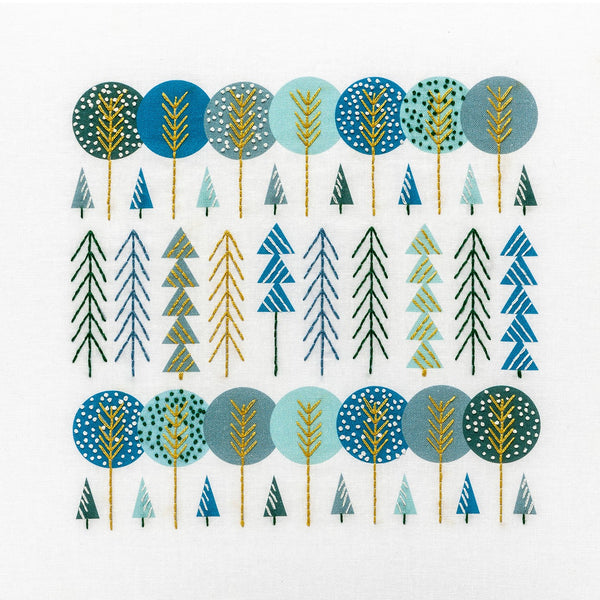 Scandinavian trees embroidery kit showing groups of trees stitched in navy, aqua, gold and green DMC thread colours