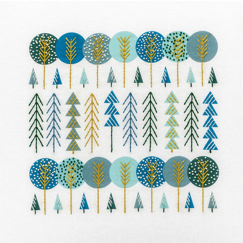 Scandinavian trees embroidery kit showing groups of trees stitched in navy, aqua, gold and green DMC thread colours
