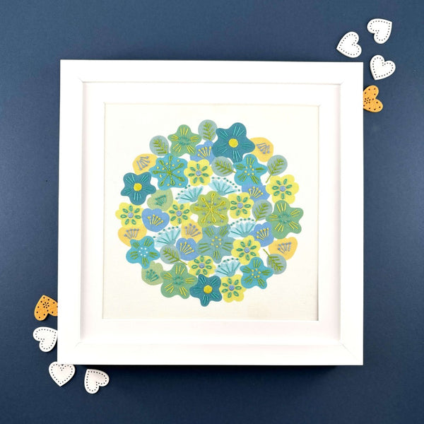 Spring flowers embroidery in a square white frame. Shown with white hearts on a navy blue background.