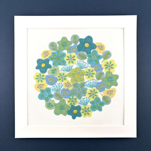 Spring flowers embroidery in a square white mount on a dark blue background.