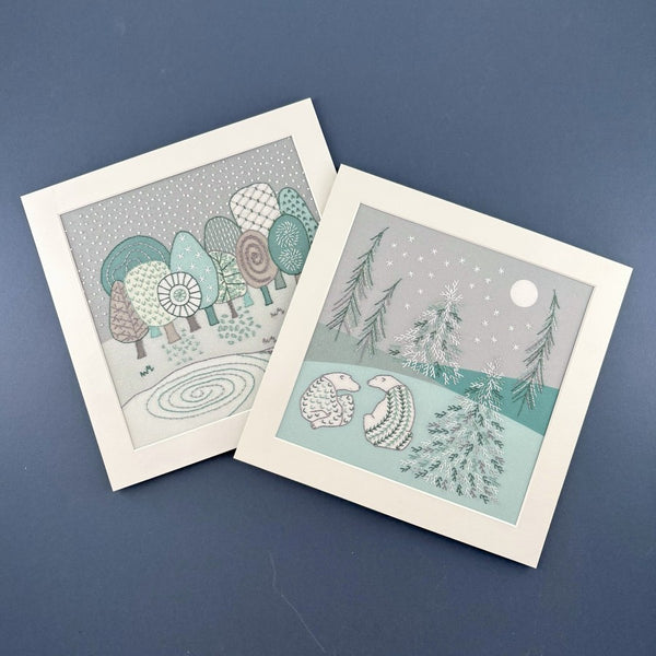 The bears embroidery pattern is shown with the winter embroidery pattern, both in square white mounts on a navy blue background.