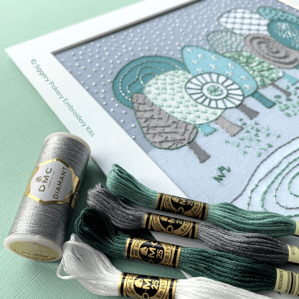 Winter embroidery shown in white square mount with DMC threads in green, grey, white and metallic