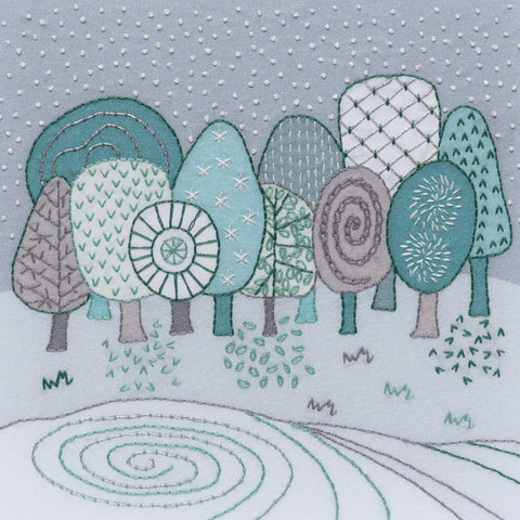 This embroidery kit creates a winter landscape of trees and a frozen lake. The stitching is done in silver metallic thread and DMC threads in 