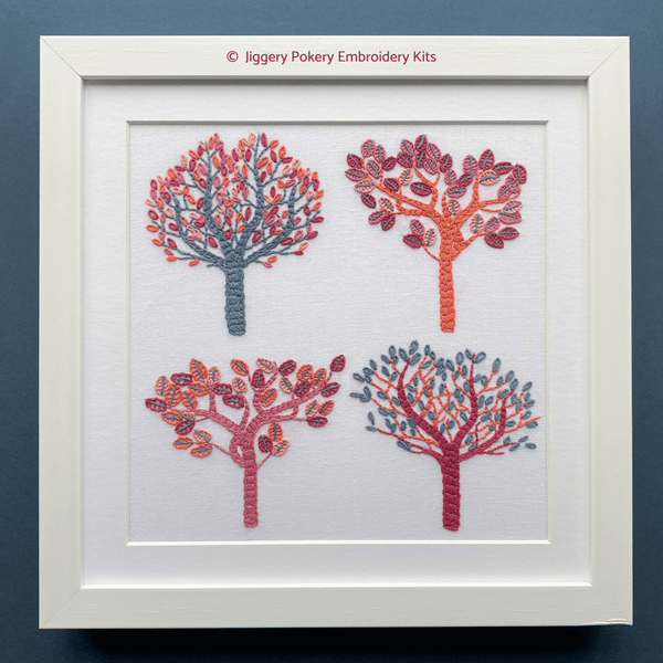 Framed autumn trees embroidery pattern showing four trees in fall colors on blue background