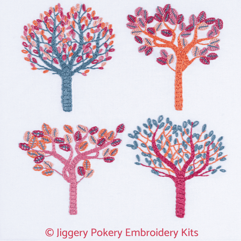 Autumn leaves embroidery kit showing four trees stitched in gunmetal grey, salmon, orange, crimson and raspberry