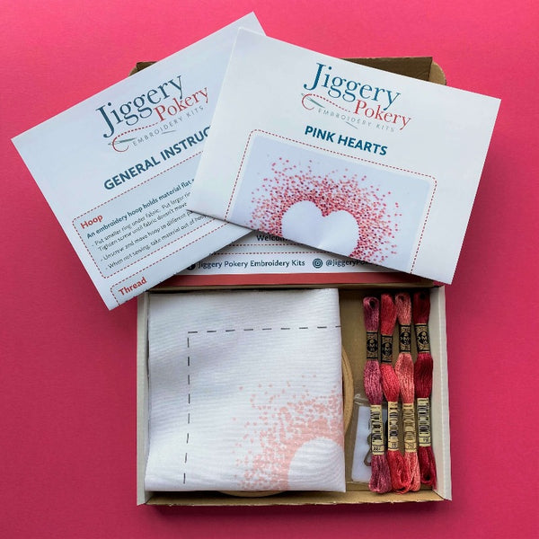 Pink hearts embroidery kit contents, shown in a box on pink background