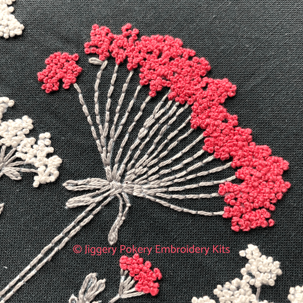 Close-up of easy flowers hand embroidery pattern showing French knots in shocking pink on pale grey stems
