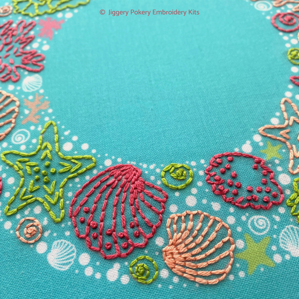 Close-up of Jiggery Pokery ocean embroidery wreath showing seashells and starfish in pink, green and coral colours