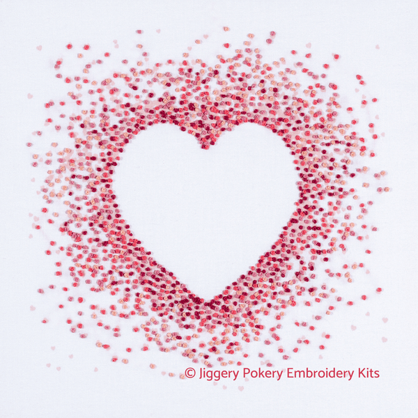 Pink hearts embroidery kit showing a negative heart shape created by French knots in pale pink, red, crimson and shocking pink