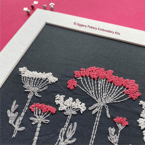 Close-up of wildflower embroidery in white mount on pink background